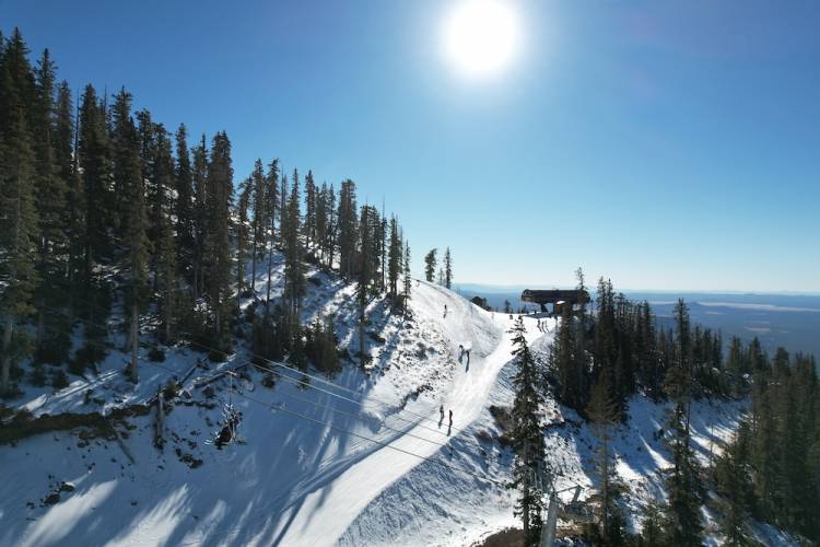 Skiers descending down a mountain run on a clear day at Arizona Snowbowl Resort