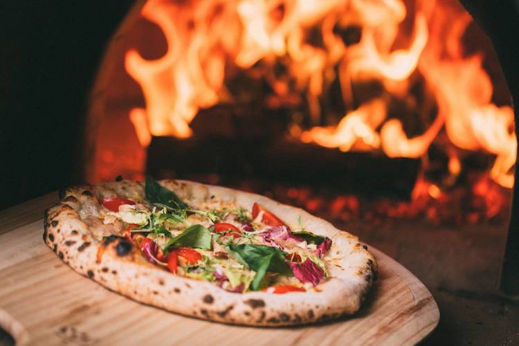 Pizza in front of a wood-fire oven