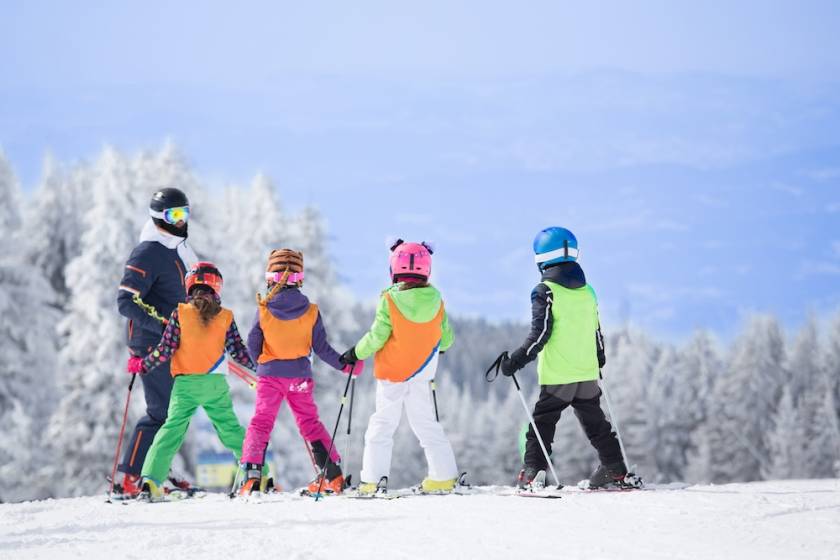 Four children on skis receiving learning from a ski instructor