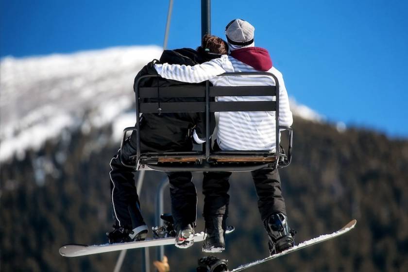 A couple with snowboards sitting on a ski lift