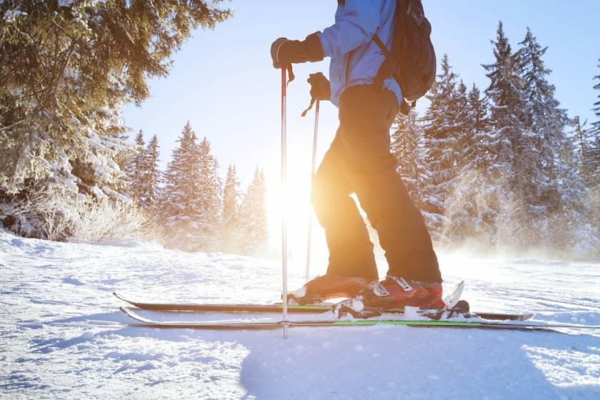 Closeup of a person skiing in between tall evergreen trees